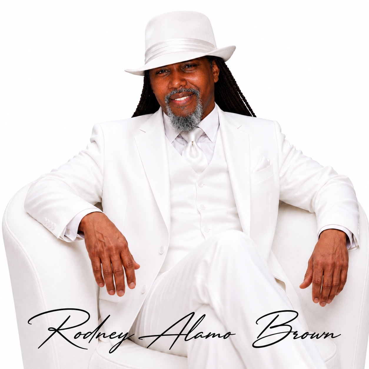 Rodney Alamo Brown seated in an all-white suit and white fedora